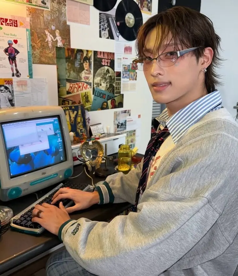 keeho from p1harmony typing on a computer, smiling awkwardly in our direction